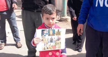 طفل يدعو للمشاركة فى الانتخابات بكفر الشيخ رافعا صور شهداء الكتيبة 103
