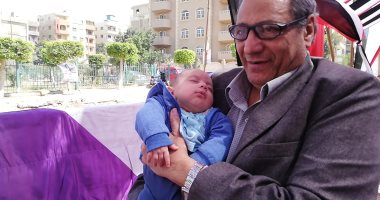 صور.. جد يحمل حفيده أثناء المشاركة فى استفتاء الدستور