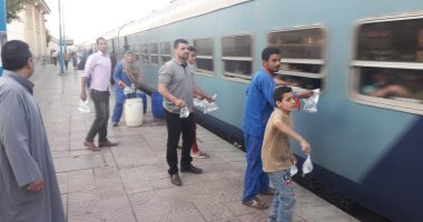 صور.. شباب متطوعون يوزعون وجبة إفطار على ركاب القطارات بمحطة الفشن