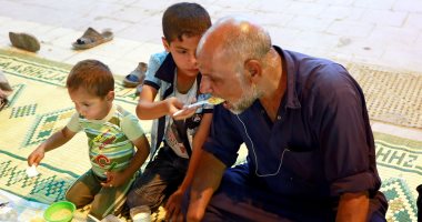 شاهد.. طفل عراقى يطعم والده المبتورة يداه فى إفطار رمضان