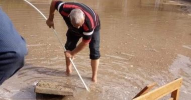 معلم يخلع حذاءه ويسلك البالوعات لتصريف مياه الأمطار فى مدرسة بدمياط