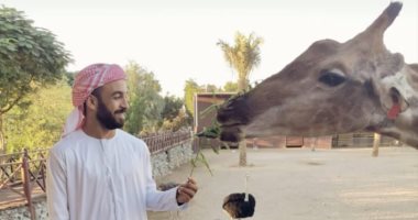 محمد مجدى قفشة يعرض صوراً بالزى الخليجى مع زرافة