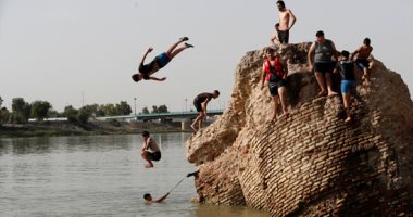 عراقيون يهربون من حرارة الجو إلى القفز فى نهر دجلة للسباحة وصيد الأسماك
