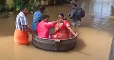 عروسان يستقلان إناء طهى عملاق للوصول إلى مقر زفافهما بسبب فيضانات الهند.. فيديو