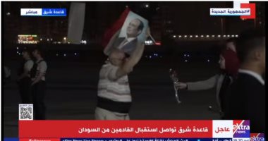 مواطن عائد من السودان على متن الطائرة العاشرة يرفع صورة الرئيس السيسى وعلم مصر