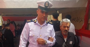 رجل شرطة يساعد مسنا للوصول إلى لجنته الانتخابية فى حدائق القبة (صورة)