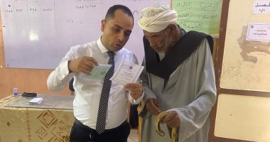 قاضٍ يساعد مسنًا فى الإدلاء بصوته داخل لجنة كيما أسوان