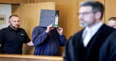 المتهم يخفي وجهه أثناء دخوله قاعة المحكمة