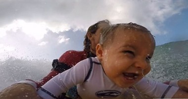 بالفيديو.. أمريكى يعلم طفله الرضيع ركوب الأمواج