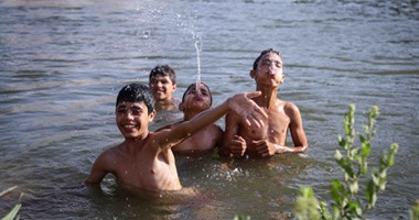 الأطفال يهربون من الحرارة المرتفعة بالاستحمام فى مياه النيل