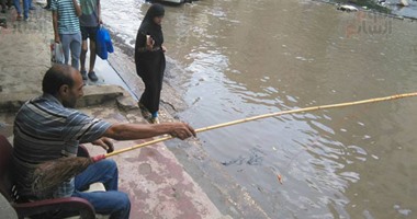 بالصور.. مواطن يحتج على غرق شوارع شبر الخيمة فى مياه الصرف بصنارة صيد سمك