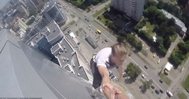 بالصور.. شاب روسى يتأرجح بين يدى صديقه فوق 40 طابقا من الأرض