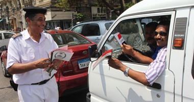 رجال المرور والشرطة النسائية يوزعون أعلام مصر احتفالا بقناة السويس