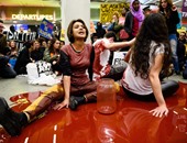 بالصور..نشطاء إنجليز يجلسون فى "بركة دم " اعتراضا على منع دخول اللاجئين