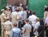 رجال الشرطة يساعدون سيدة مسنة للدخول للجان التصويت بمدرسة الشيخ زايد