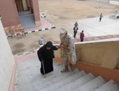 جندى بالقوات المسلحة يساعد سيدة مسنة فى دخول لجنة انتخابية بسوهاج