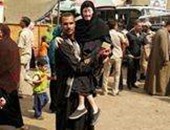 شاب يحمل والدته المسنة للإدلاء بصوتها فى لجنة انتخابية بمنفلوط