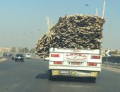 قارئ يرصد سيارة نصف نقل بحمولة زائدة من الأخشاب تسير أعلى الطريق الدائرى