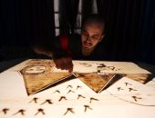 بالصور .. " مايكل رومانى" رسام مصرى يفصح عن ثقافة بلاده من خلال الرسم على الرمال