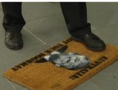 بالفيديو.. سيناتور أسترالى يدهس بقدمه "ممسحة أرجل" عليها صورة ترامب