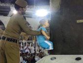 بالصور.. رجل أمن سعودى يساعد طفلا فى تقبيل الكعبة الشريفة