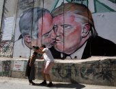 بالصور.. سيلفى العاشقين أمام جرافيتى قبلة "ترامب" و"نتنياهو" بالضفة الغربية