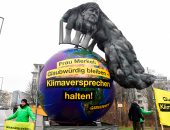 صور.. أعضاء منظمة السلام الأخضر ببرلين يتظاهرون بصورة لميركل ملطخة بالضباب الدخانى