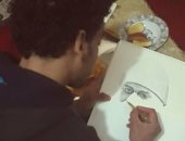 "علاء حركات" يبدع فى رسم لوحاته الفنية مستخدماً الفحم والرمل