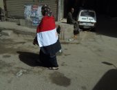 عجوز ترتدى علم مصر وتجوب شوارع فيصل لحث المواطنين على المشاركة بالانتخابات