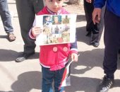 طفل يدعو للمشاركة فى الانتخابات بكفر الشيخ رافعا صور شهداء الكتيبة 103