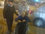 أفراد الأمن يحملون مسنا على كرسى متحرك للإدلاء بصوته فى الدقى