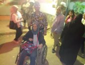 صور.. قوات تأمين لجنة بالزاوية يحملون مسنة على كرسى متحرك