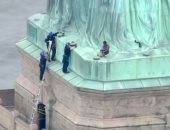 صور وفيديو..سيدة تتسلق قاعدة تمثال الحرية فى نيويورك والشرطة تخلى المنطقة