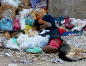 صور.. سيدة تعيش وسط الكلاب الضالة وتأكل وتشرب من القمامة ببورسعيد 