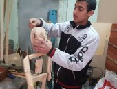 صور.. أحمد عوض يتحدى الإعاقة بالفن ويعبر عن نفسه بالرسم على الخشب