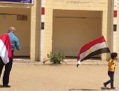 فيديو.. مشهد وطنى.. الجد فى إيده حفيدة بعلم مصر أثناء الاستفتاء بالرماية