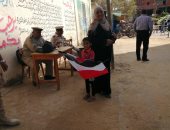 سيدة ببنى سويف تصطحب طفلها أثناء التصويت بالاستفتاء.. وتؤكد: بعلمه الانتماء