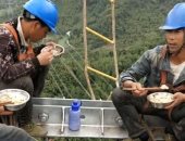 بأحزمة الأمان.. عمال كهرباء صينيون يناولون الطعام على ارتفاع 130 مترا..صور 