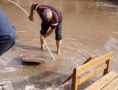 معلم يخلع حذاءه ويسلك البالوعات لتصريف مياه الأمطار فى مدرسة بدمياط