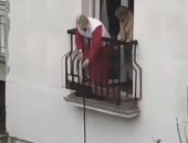 "في زمن كورونا" مسنة تنزل كلبها من شرفة منزلها لأخذ نزهة في الهواء.. فيديو