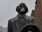 تمثال الكاتب الجالس فى أسيوط بـ"الكمامة" يثير الجدل..وآخرون: لتوعية المواطنين