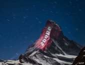 من وسط العتمة نور.. فنان يتحدى كورونا بـ"رسائل الأمل" على قمة جبل بسويسرا