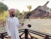 محمد مجدى قفشة يعرض صوراً بالزى الخليجى مع زرافة