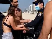 شرطي إسرائيلي يضع كلبشات في يد فتاة على أحد شواطئ تل أبيب بسبب كورونا.. فيديو