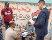 رئيس لجنة انتخابية يساعد أحد كبار السن فى الإدلاء بصوته بالجيزة.