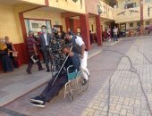 صور.. الشرطة تساعد كبار السن وذوى الهمم للوصول للجان بكراسى متحركة بالإسكندرية