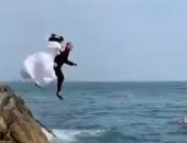 عروسان أيرلنديان يحتفلان بزواجهما بالقفز فى البحر بملابس الزفاف..فيديو وصور