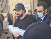 الفنان حازم إيهاب يحمل طفله الرضيع بالكفن بعد صلاة الجنازة 
