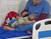 ممرض يحمل رضيعا ويداعبه داخل العناية المركزة ببنى سويف.. صورة