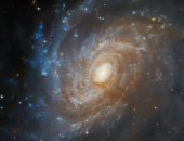 تلسكوب هابل يرصد مجرة ​​لامعة تنبثق من خلف سديم مظلم